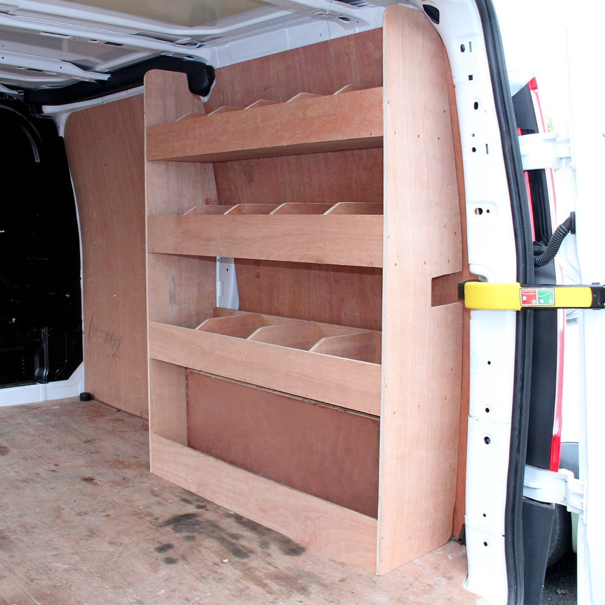 Scaffale in legno chiaro per furgone Ford Transit, con tre ripiani e spazi per contenitori, allestito su parete interna del veicolo