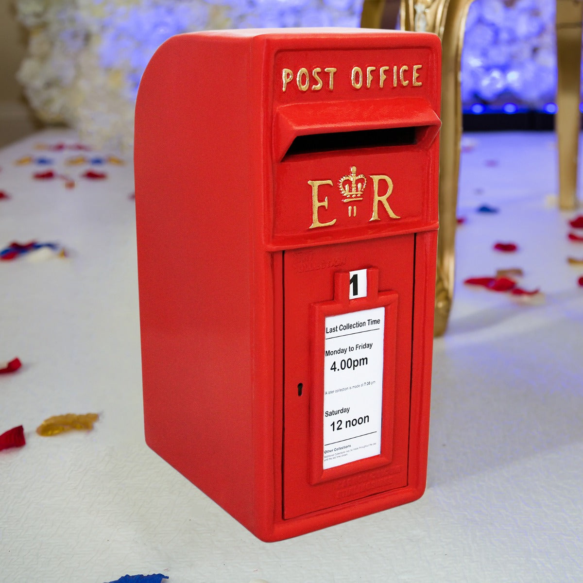 Cassetta postale britannica rossa con dettagli dorati, sportello per la raccolta e orari di apertura ben visibili