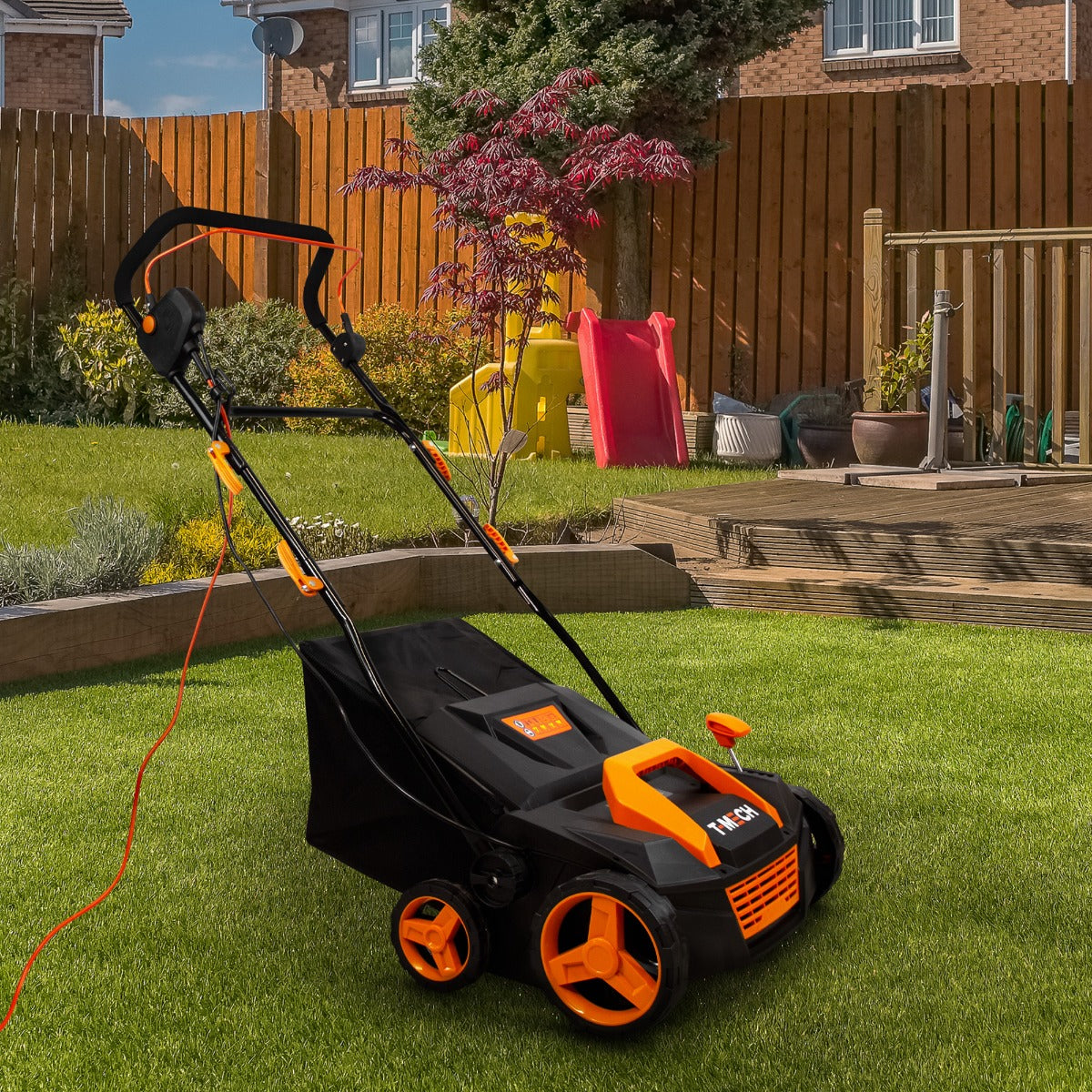 Aspiratore per erba artificiale T-Mech con struttura nera e arancione, ruote robuste, cavo elettrico e design ergonomico, ideale per giardini curati