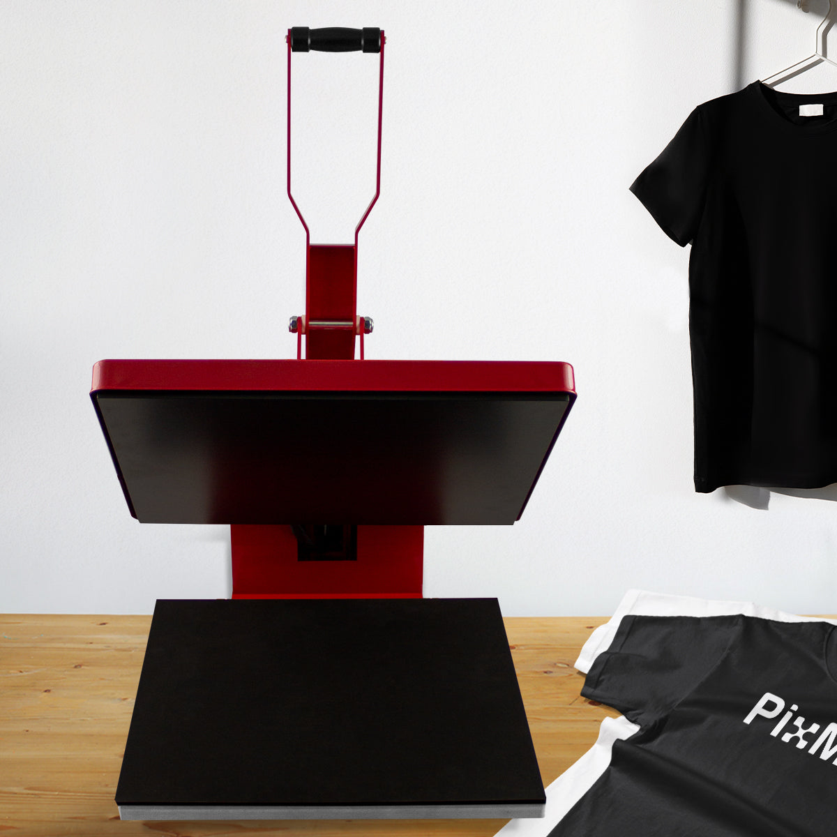 Pressa a caldo rossa 50x50 cm per sublimazione, con piano nero, ideale per stampare su magliette PixMax, su sfondo di legno chiaro