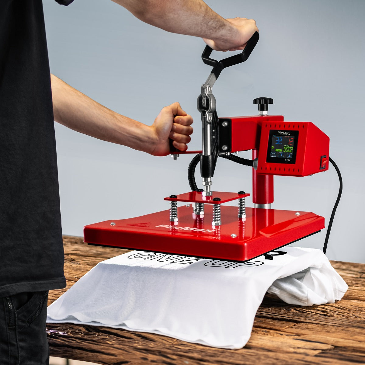 Pressa termica rossa in uso su una maglietta bianca, con manico ergonomico e display digitale per impostare temperatura e tempo