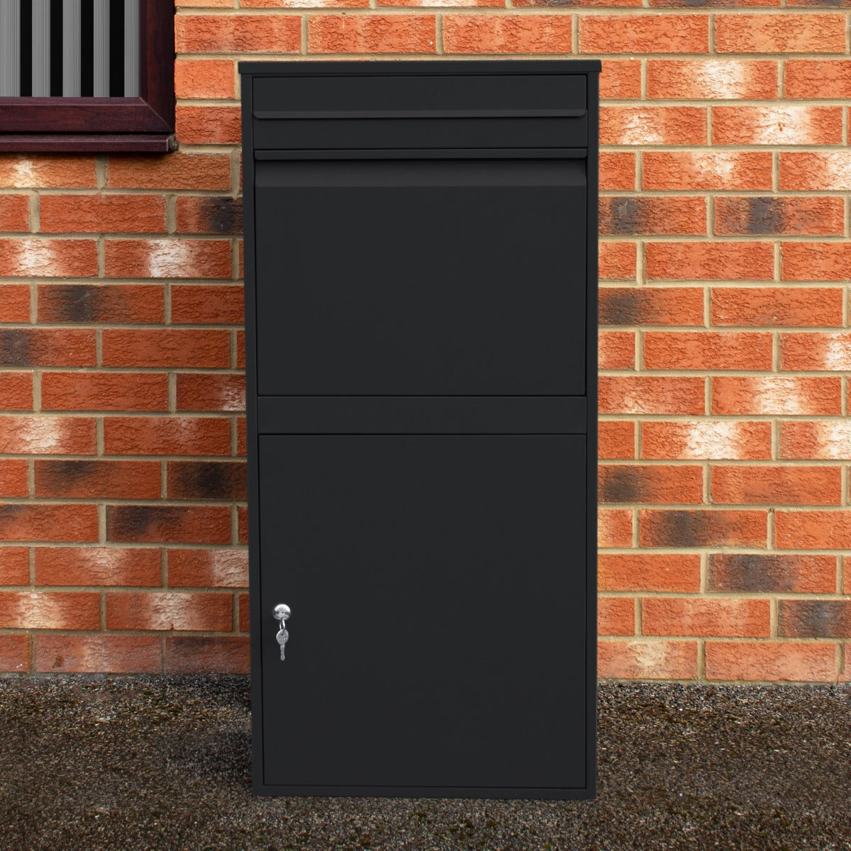 Cassetta postale XL antifurto nera, con finitura opaca, design moderno e chiusura sicura, posizionata su sfondo di mattoni rossi