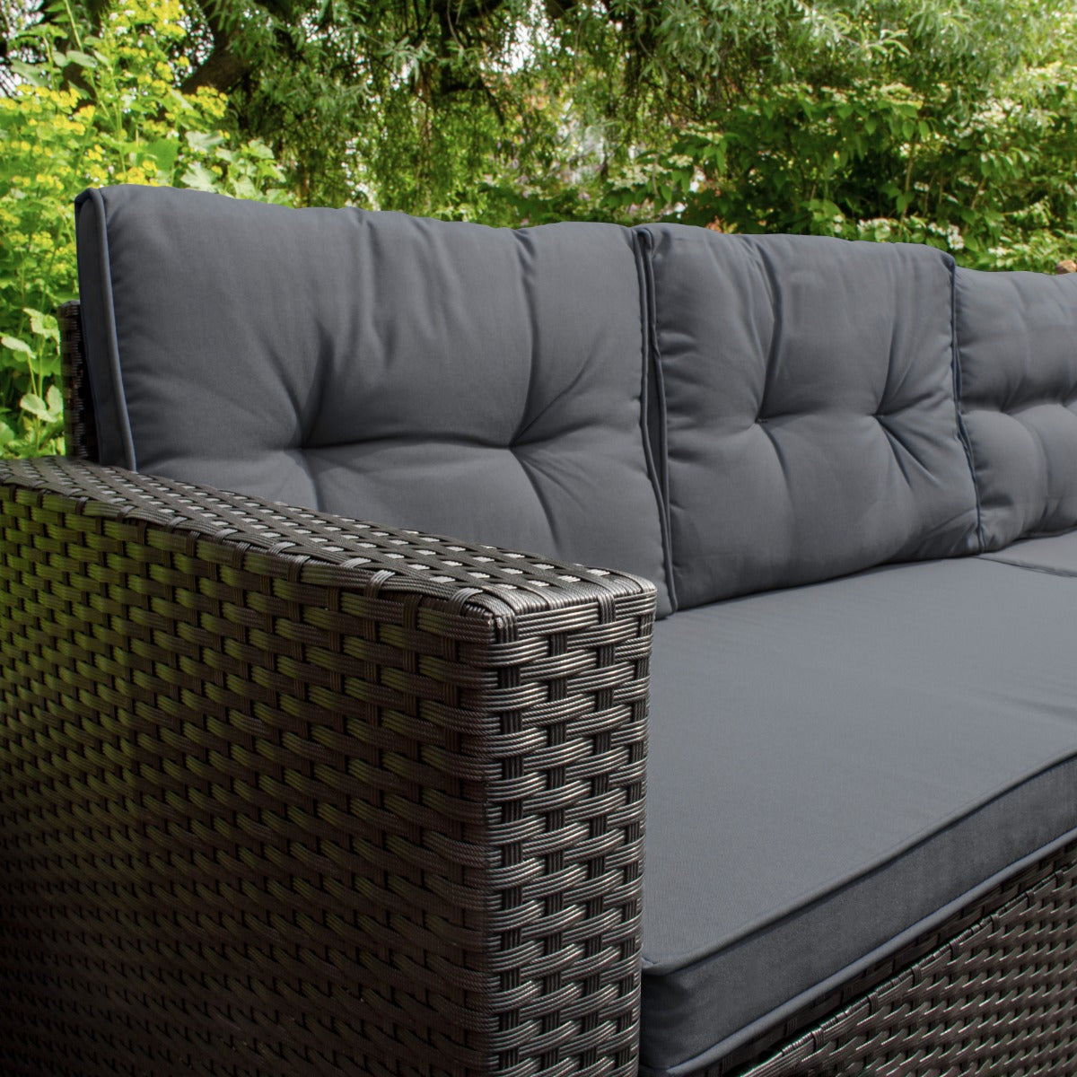 Set ad angolo in rattan nero con cuscini grigi, design elegante e texture intrecciata, ideale per esterni e giardini