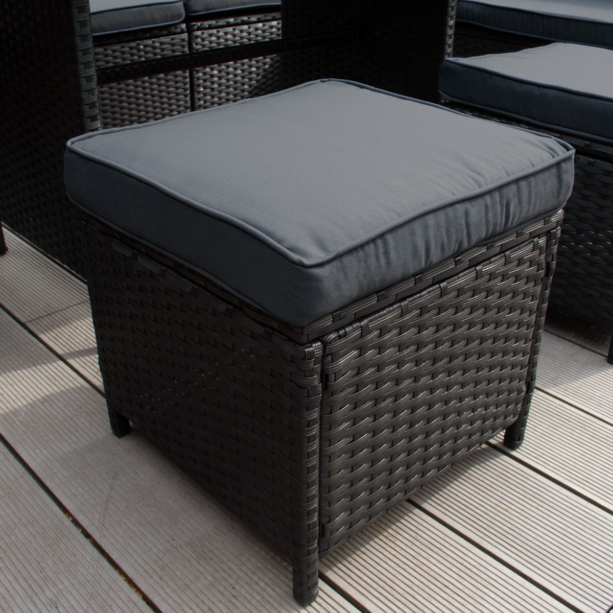 Set ad angolo in rattan nero con cuscino grigio, struttura intrecciata e finitura elegante, ideale per spazi esterni raffinati