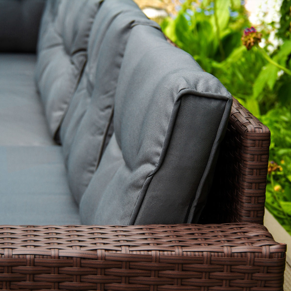 Set ad angolo in rattan marrone con cuscini grigi, design elegante e texture intrecciata, ideale per spazi esterni accoglienti