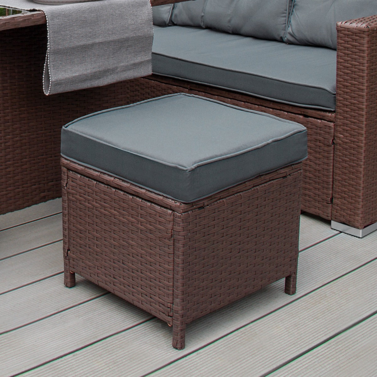 Set ad angolo in rattan marrone con cuscino grigio, texture intrecciata e forma quadrata, ideale per spazi esterni eleganti