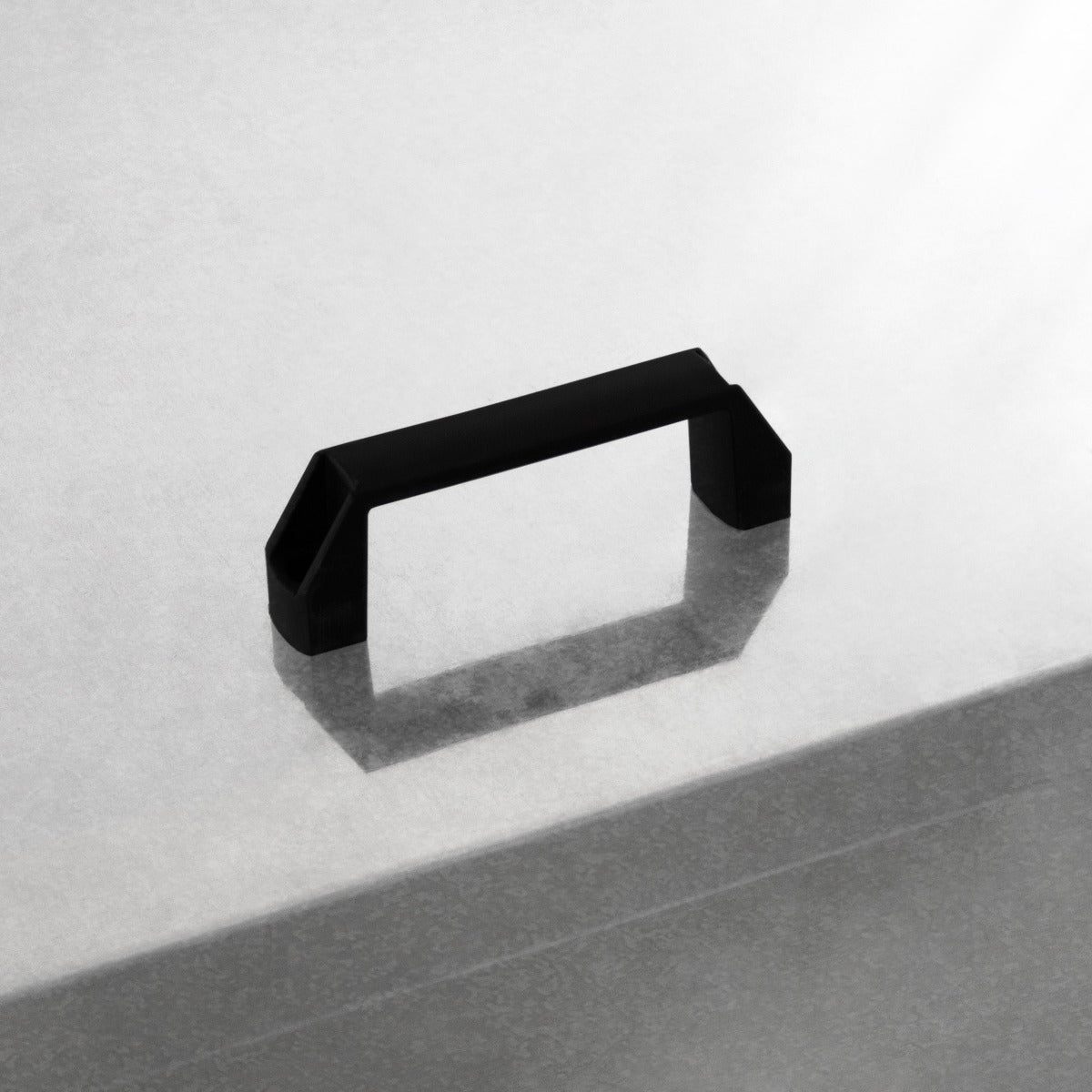 Manico nero in metallo opaco su superficie grigia, progettato per un bidone per carbone e legna da 500 kg, elegante e resistente