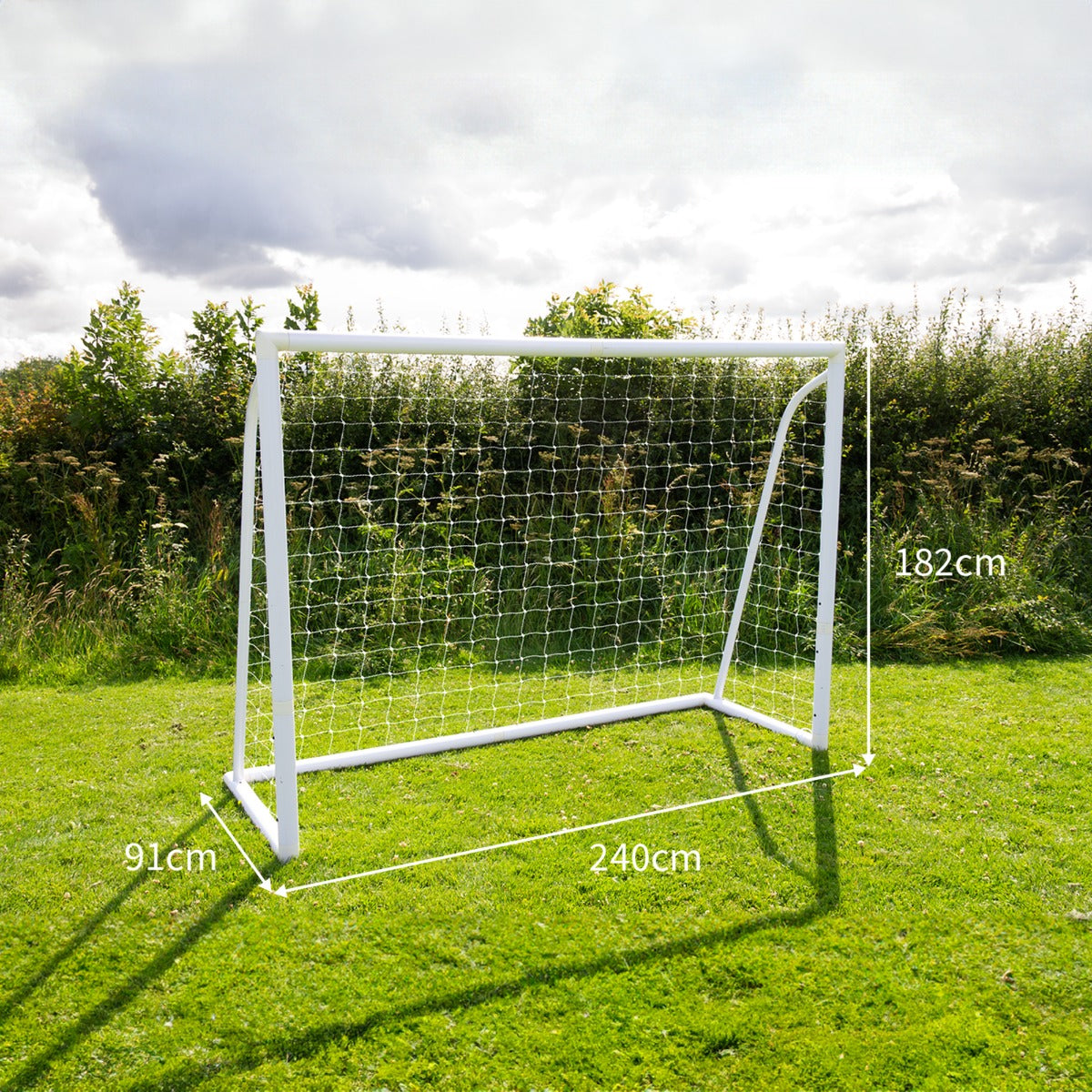 Porta da calcio bianca 240cm x 180cm con rete, posizionata su un prato verde, circondata da alberi e cielo nuvoloso