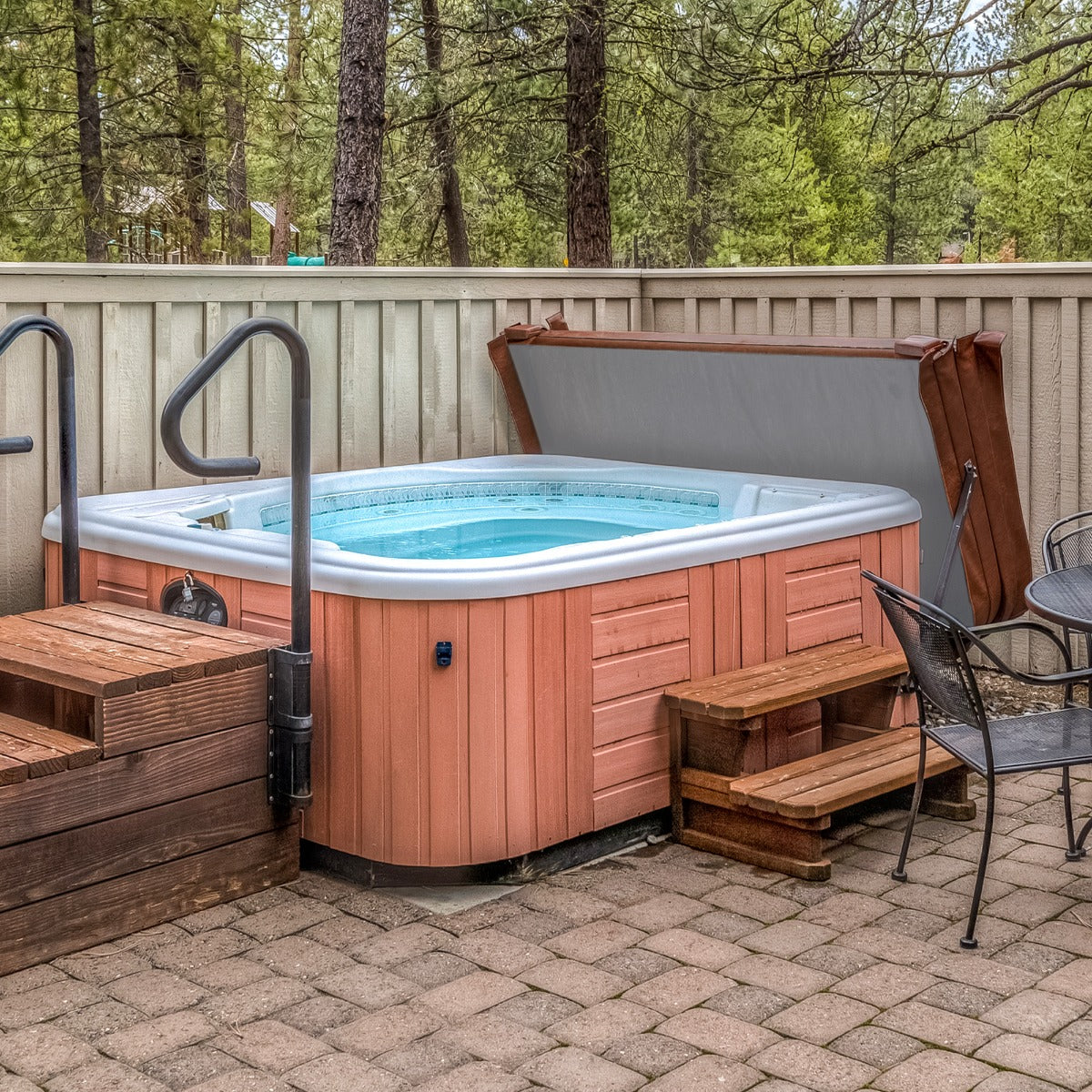 Copertura marrone per vasca idromassaggio da 2.2m, con struttura in legno e bordi curvi, posizionata in un ambiente naturale e rilassante