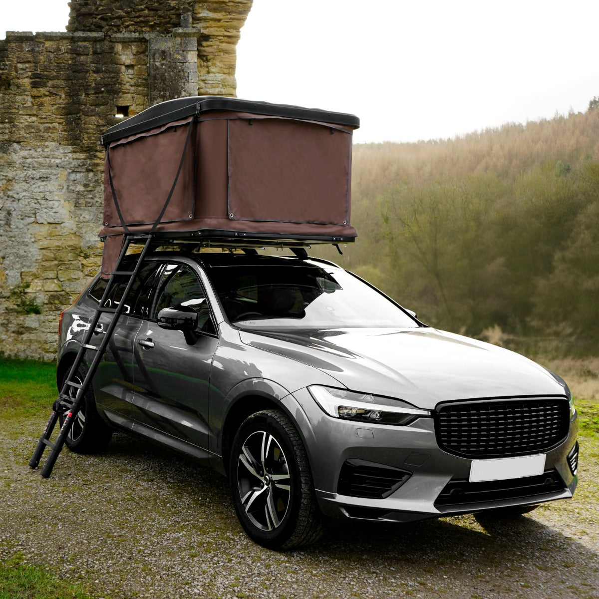 Tenda da tetto marrone montata su un'auto grigia, con struttura robusta e dettagli in tessuto resistente, ideale per il campeggio