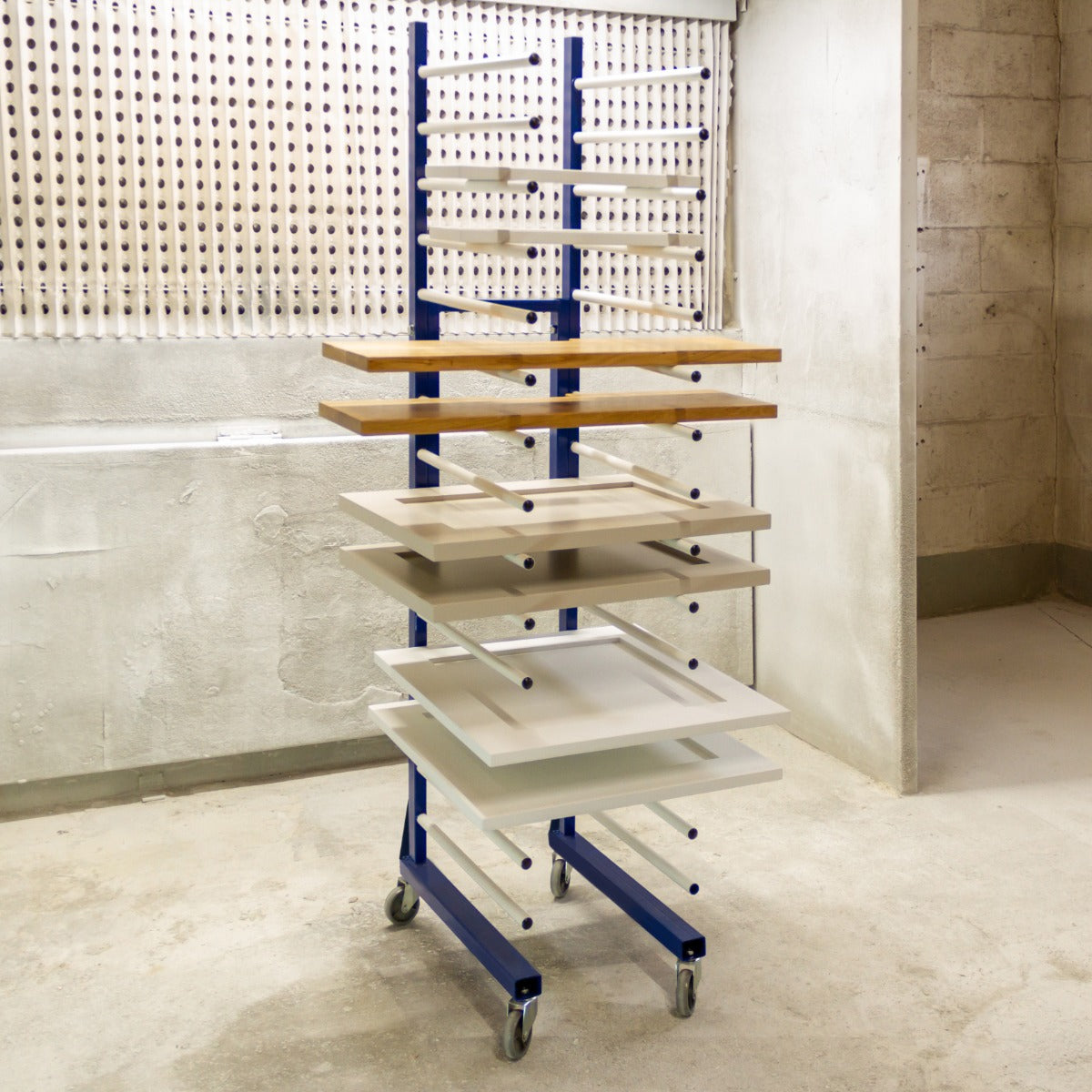 Carrello per asciugatura a spruzzo con struttura blu, ripiani in legno chiaro e bianco, ruote per facile mobilità, ideale per laboratori