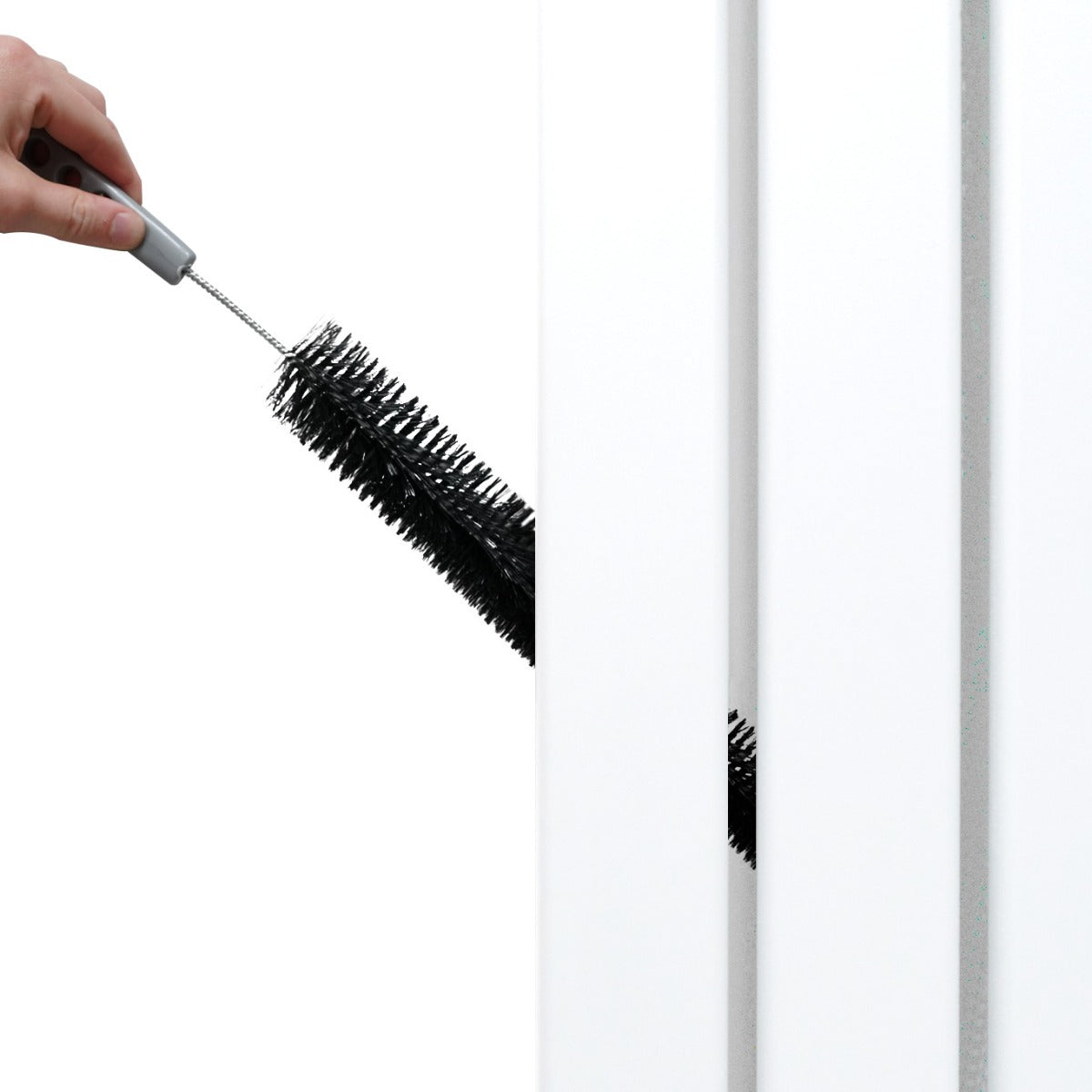 Spazzola nera per la pulizia di un radiatore a specchio piatto bianco, con dettagli eleganti e superficie liscia, in un ambiente luminoso