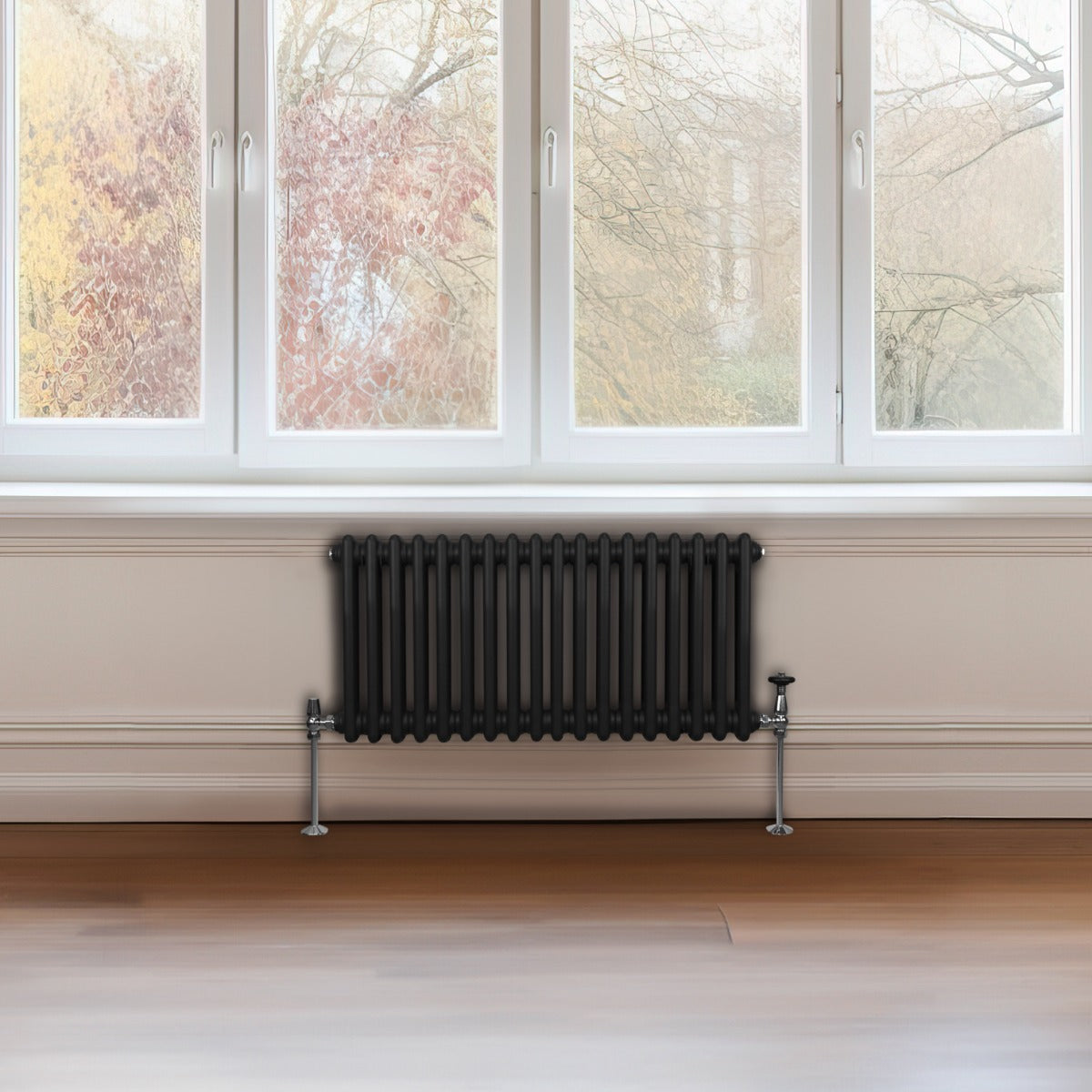 Termosifone a 2 colonne, 300 x 832 mm, finitura nera opaca, installato sotto una finestra con vista su un giardino autunnale