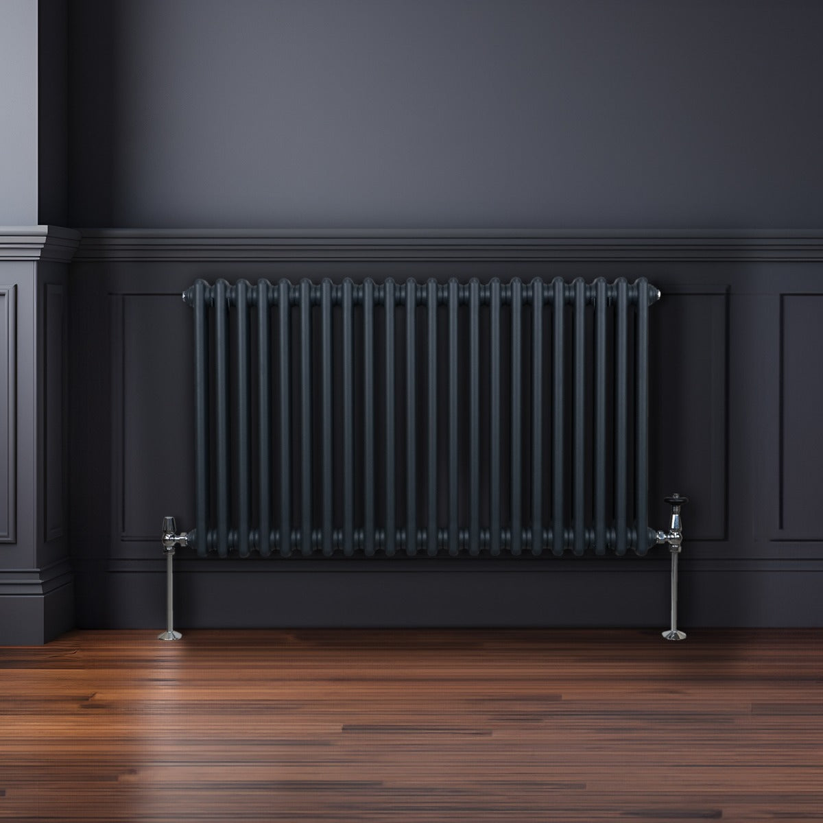 Termosifone a 2 colonne grigio antracite, con finitura liscia e tubi verticali, installato su parete scura in un ambiente elegante
