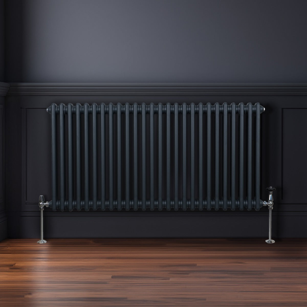 Termosifone a 2 colonne grigio antracite, con finitura liscia e tubi verticali, installato su parete scura e pavimento in legno lucido