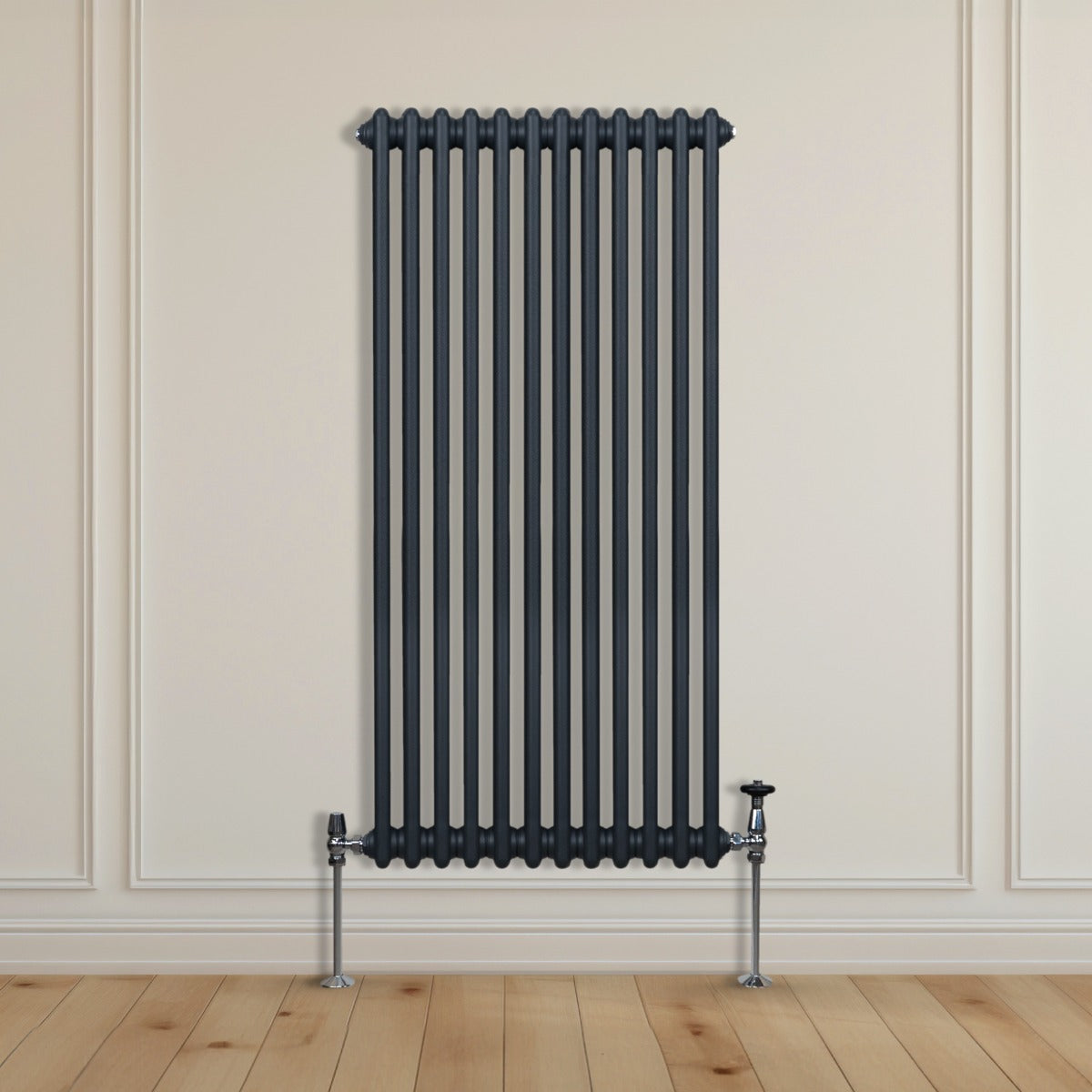 Termosifone a 2 colonne grigio antracite, alto e sottile, con tubi verticali e supporti metallici su pavimento in legno chiaro
