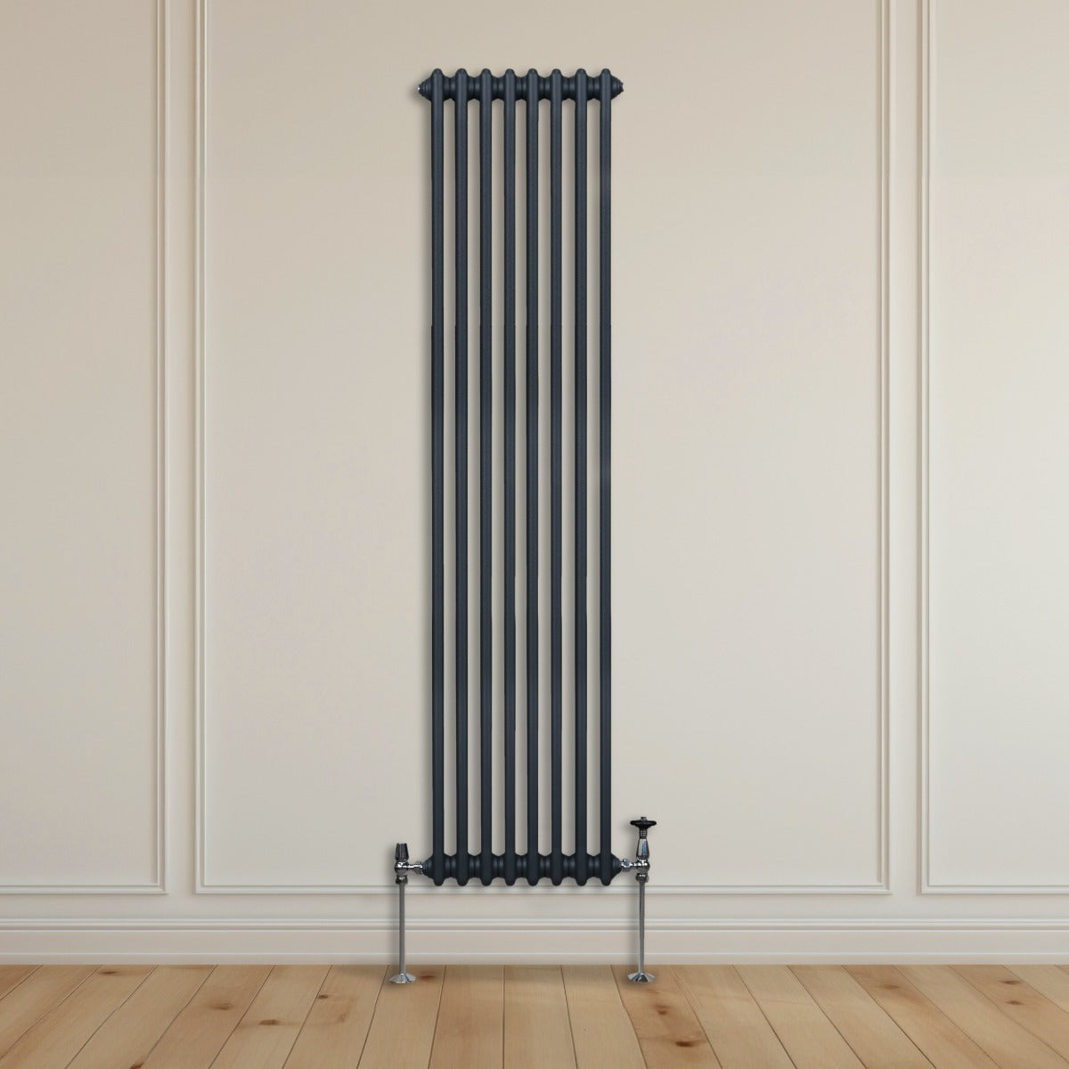 Termosifone a 2 colonne grigio antracite, alto e stretto, con finitura liscia, montato su parete bianca, accanto a pavimento in legno chiaro