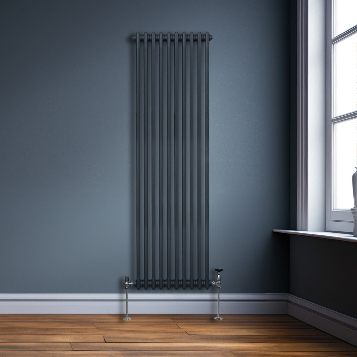 Termosifone a 2 colonne grigio antracite, alto e sottile, con finitura liscia, posizionato contro una parete blu scuro in un ambiente moderno