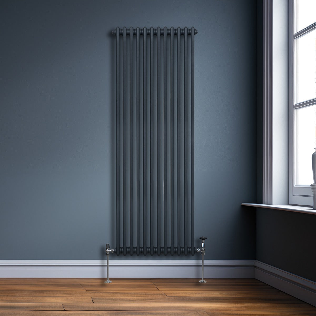 Termosifone a 2 colonne grigio antracite, elegante e moderno, installato su una parete blu, con tubi verticali e supporti metallici lucidi