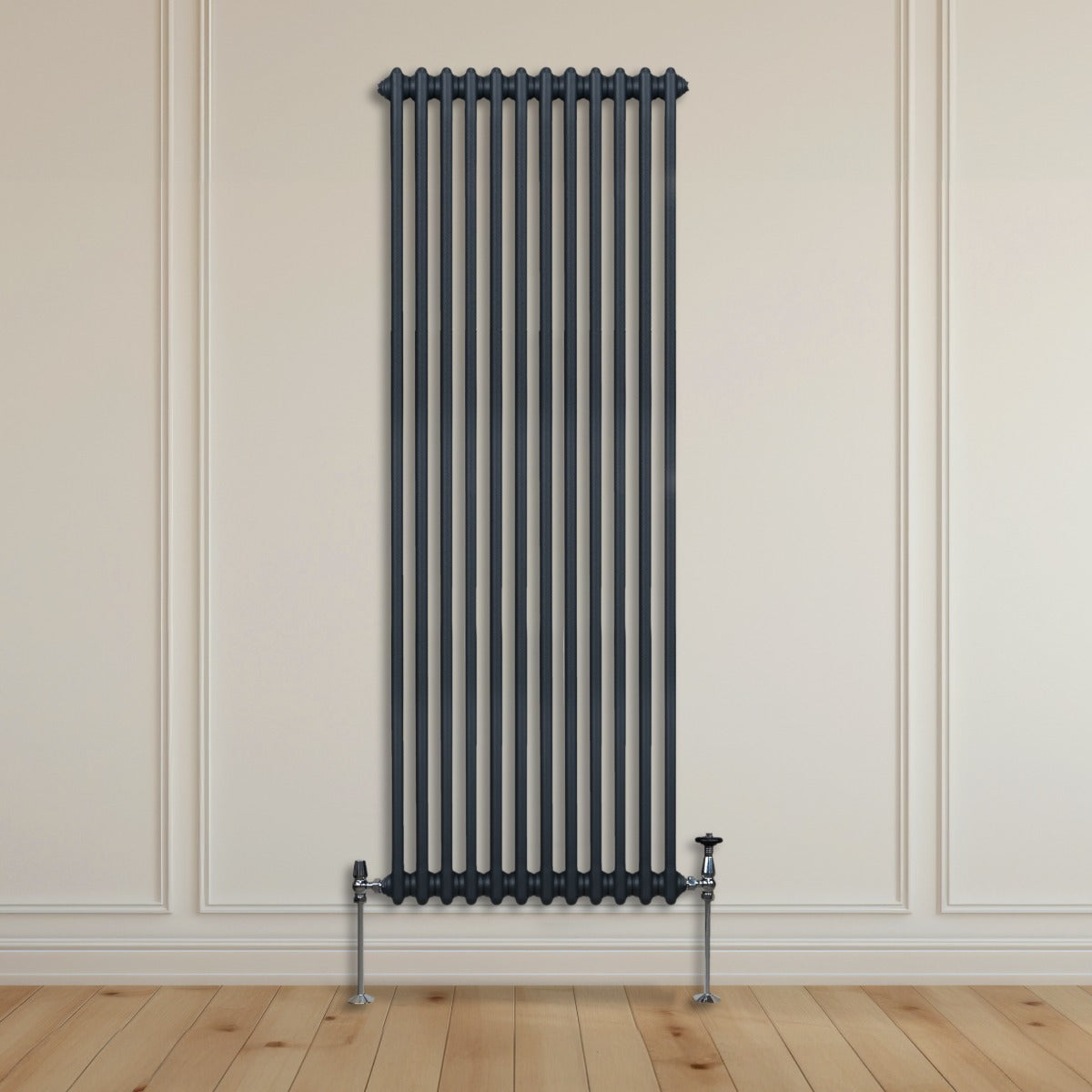 Termosifone a due colonne grigio antracite, alto e stretto, con tubi verticali e supporti metallici, posizionato su parete chiara