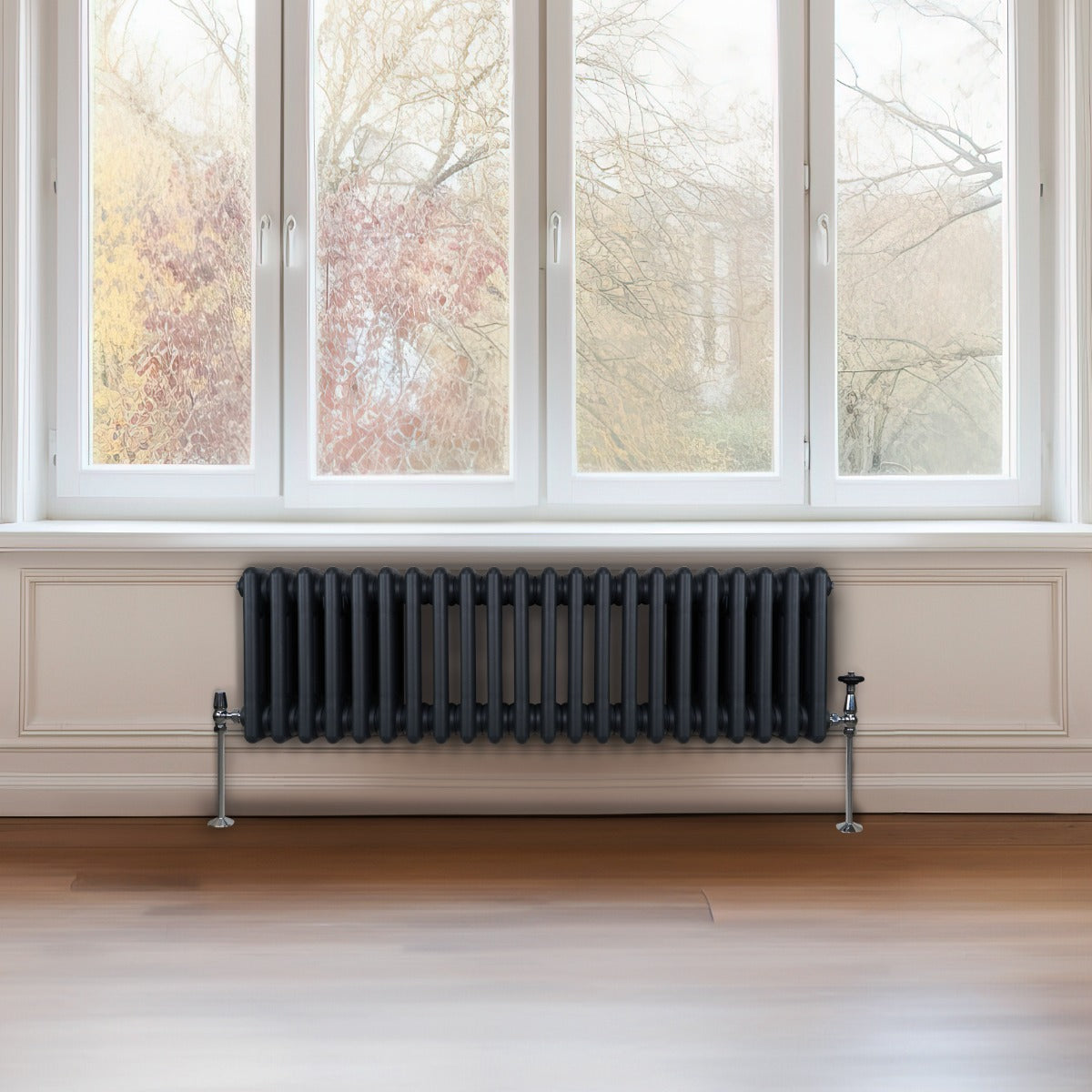 Termosifone a 3 colonne in grigio antracite, con finitura liscia e tubi verticali, posizionato sotto una grande finestra