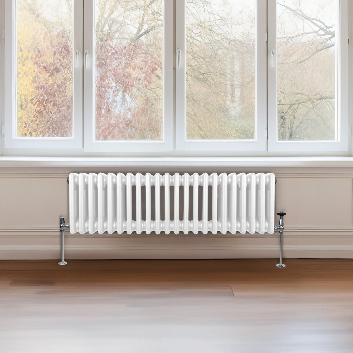 Termosifone a 3 colonne bianco, lungo 300 mm e alto 1012 mm, con finitura lucida e supporti metallici, posizionato sotto una finestra