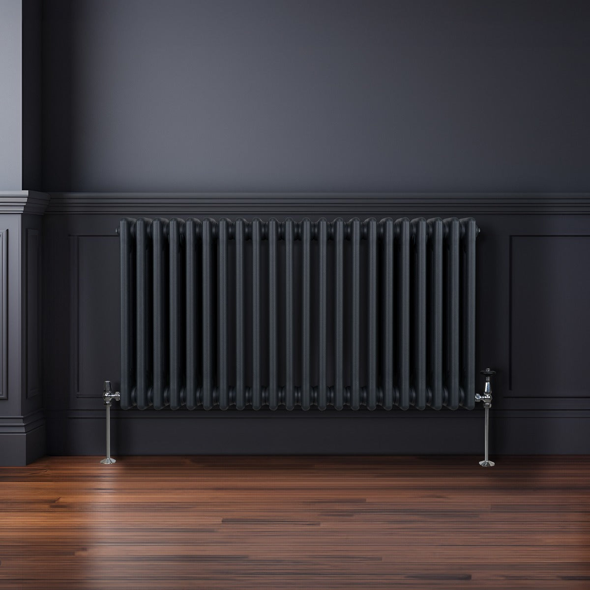Termosifone a 3 colonne grigio antracite, con finitura liscia, installato su parete scura, su pavimento in legno lucido