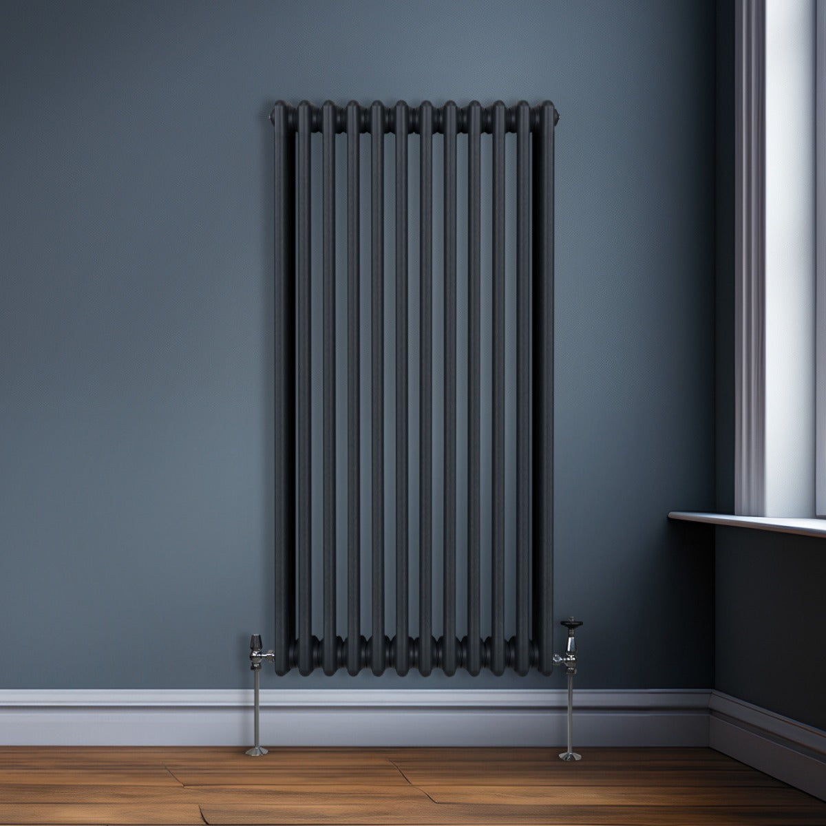 Termosifone a 3 colonne grigio antracite, con finitura liscia e tubi verticali, installato su parete blu in un ambiente moderno