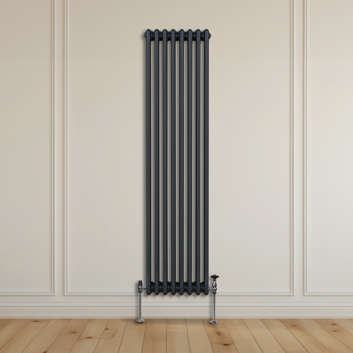 Termosifone a 3 colonne grigio antracite, alto e sottile, installato su una parete chiara, con tubi metallici e valvola in basso