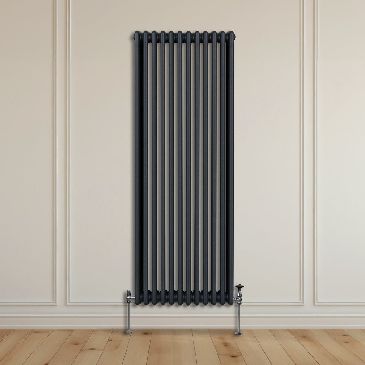 Termosifone a 3 colonne grigio antracite, alto e stretto, con finitura liscia e tubi verticali, installato su parete chiara in legno