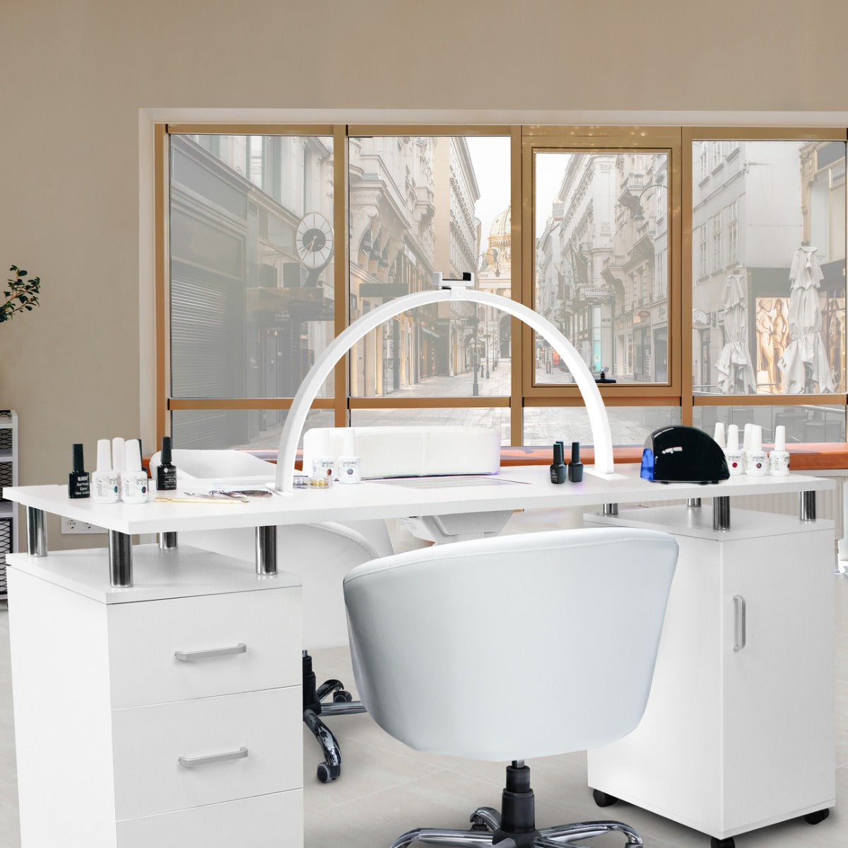 Tavolo da manicure bianco con lampada LED a mezzaluna, circondato da prodotti per unghie e una sedia ergonomica grigia