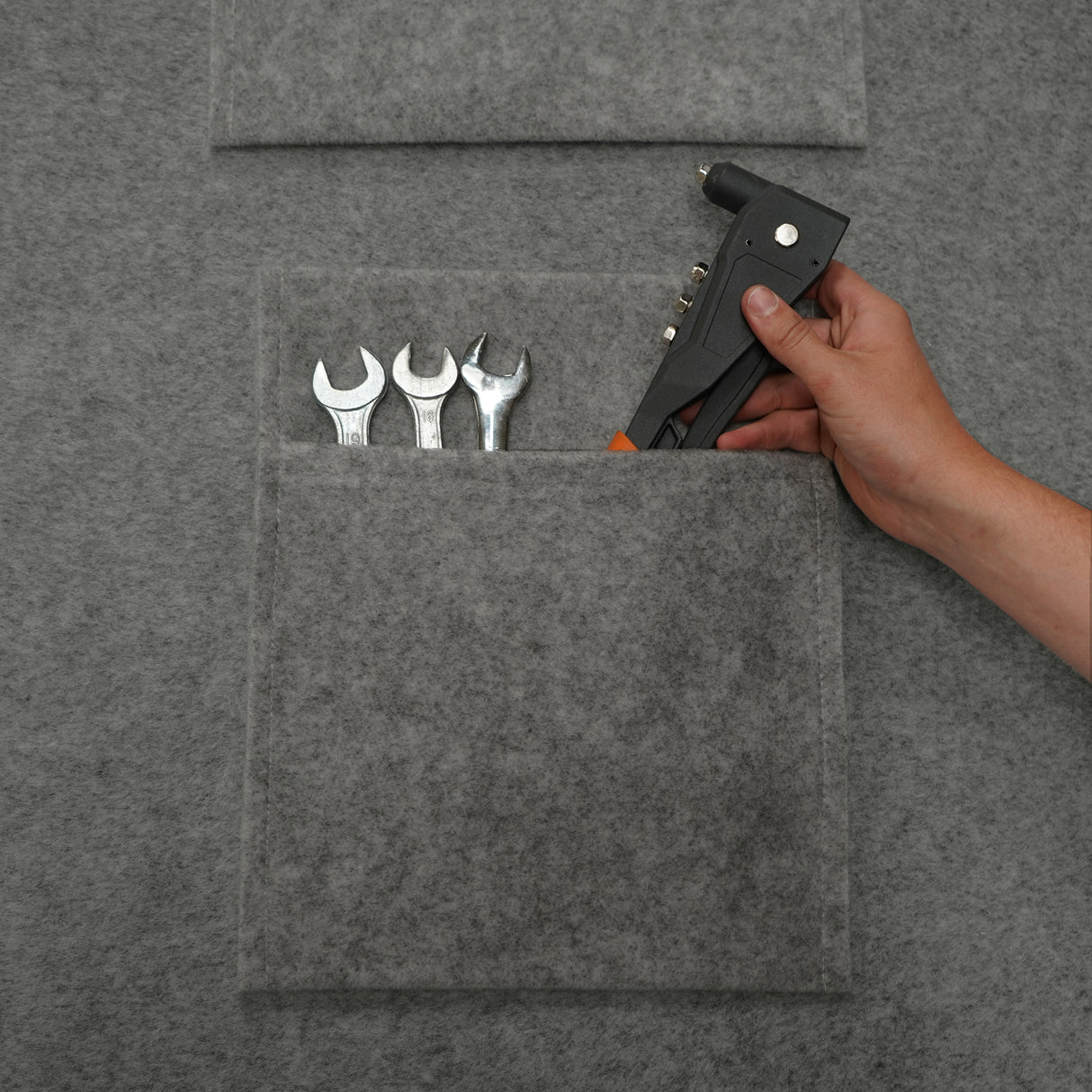 Tasche portaoggetti in grigio fumo con texture in feltro, contenenti chiavi inglesi e una pistola per colla, pratiche e funzionali