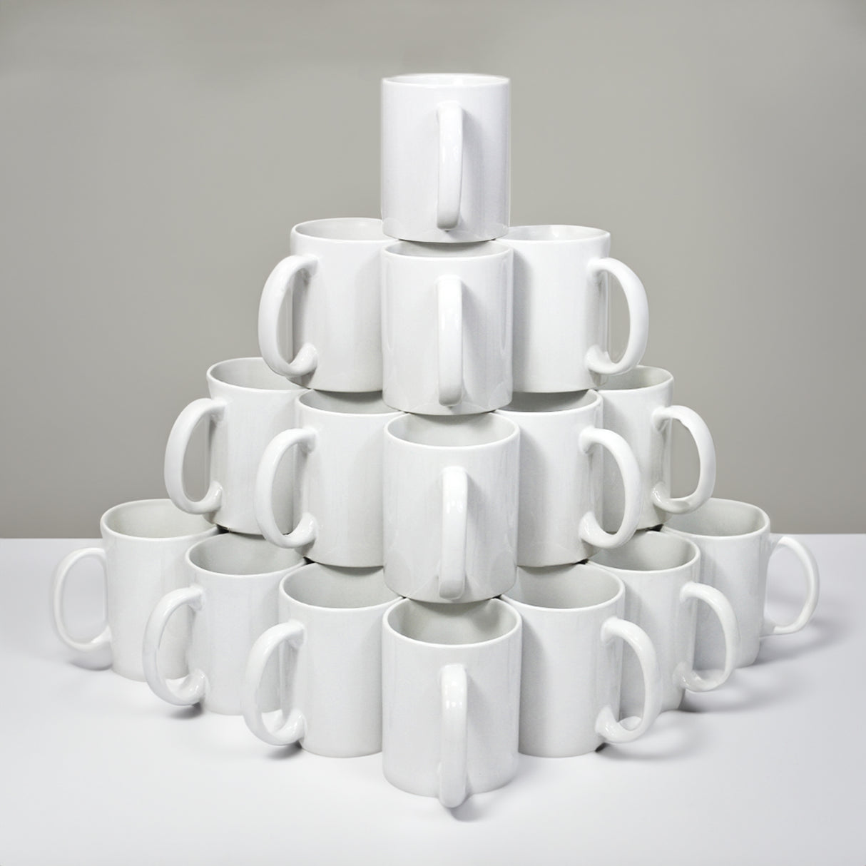 Tazze bianche in ceramica per sublimazione, impilate a piramide, con manici ergonomici e superficie liscia per personalizzazione