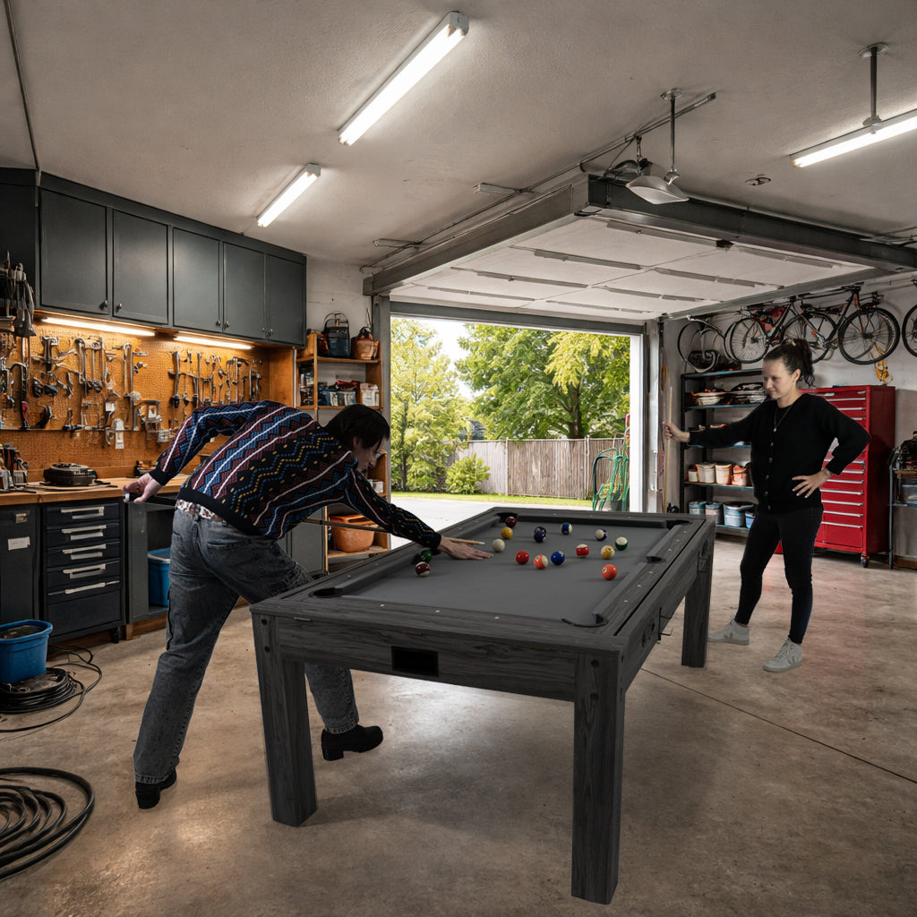 Tavolo giochi 7-in-1 grigio con superficie liscia, freccette e luci LED, utilizzato da due persone in un garage ben attrezzato