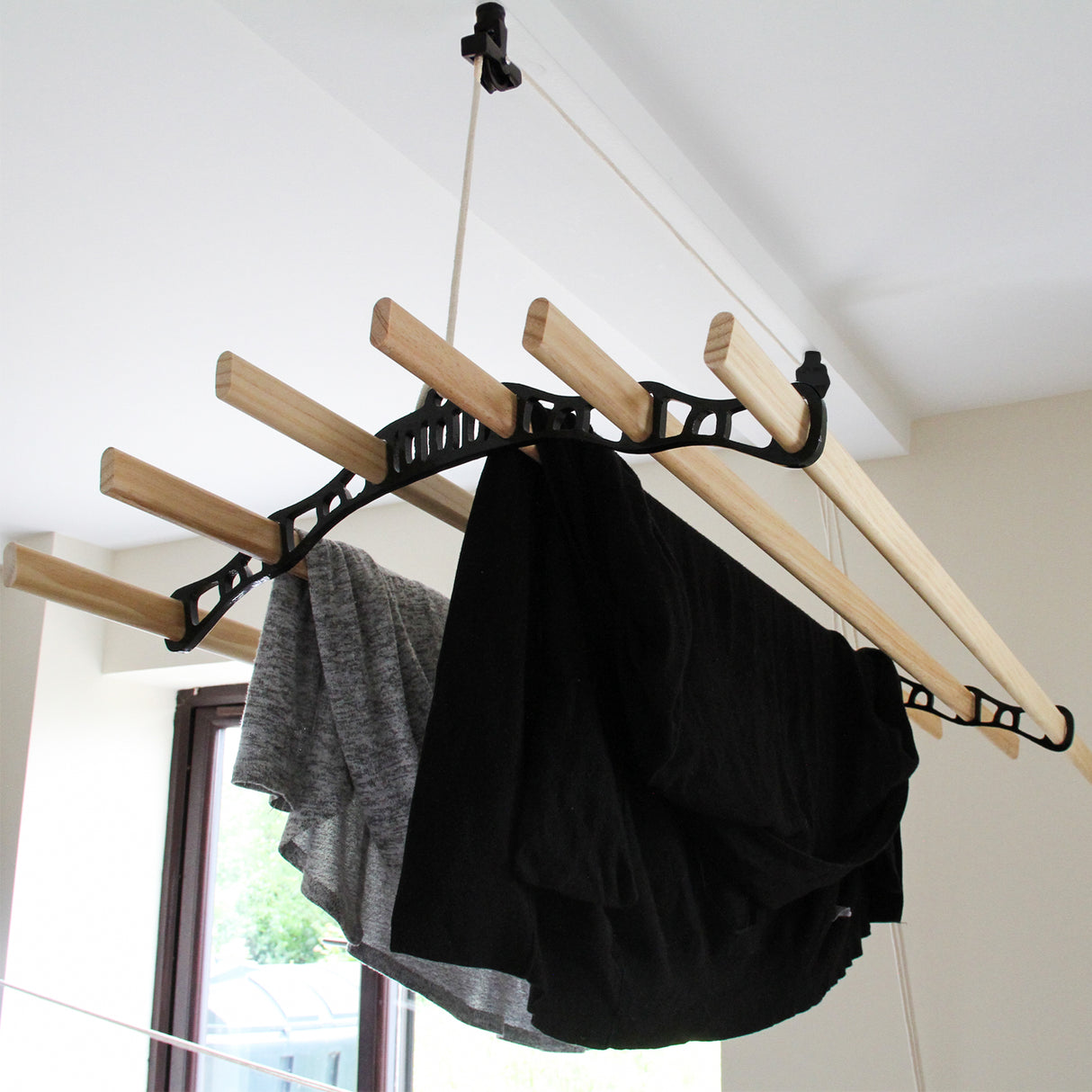 Stendibiancheria da soffitto nero di 180 cm con barre in legno, tessuti neri e grigi appesi, design funzionale e moderno