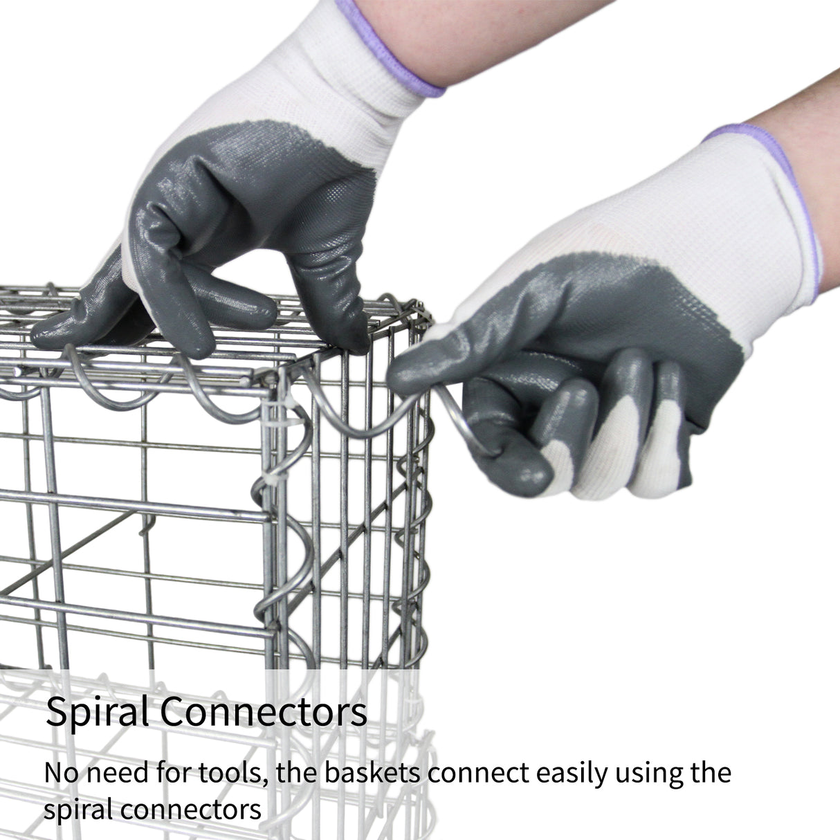 Mani con guanti grigi e bianchi che collegano gabbioni metallici zincati con connettori a spirale, evidenziando la facilità d'uso