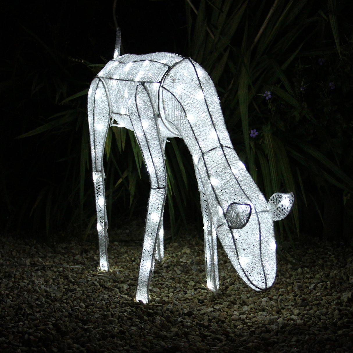 Renna di Natale luminosa femmina, realizzata in metallo bianco, decorata con luci LED, posizionata su un fondo di ghiaia scura