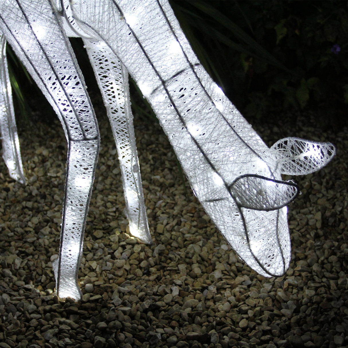 Renna di Natale luminosa femmina, realizzata in tessuto bianco con dettagli luminosi, posizionata su ghiaia decorativa