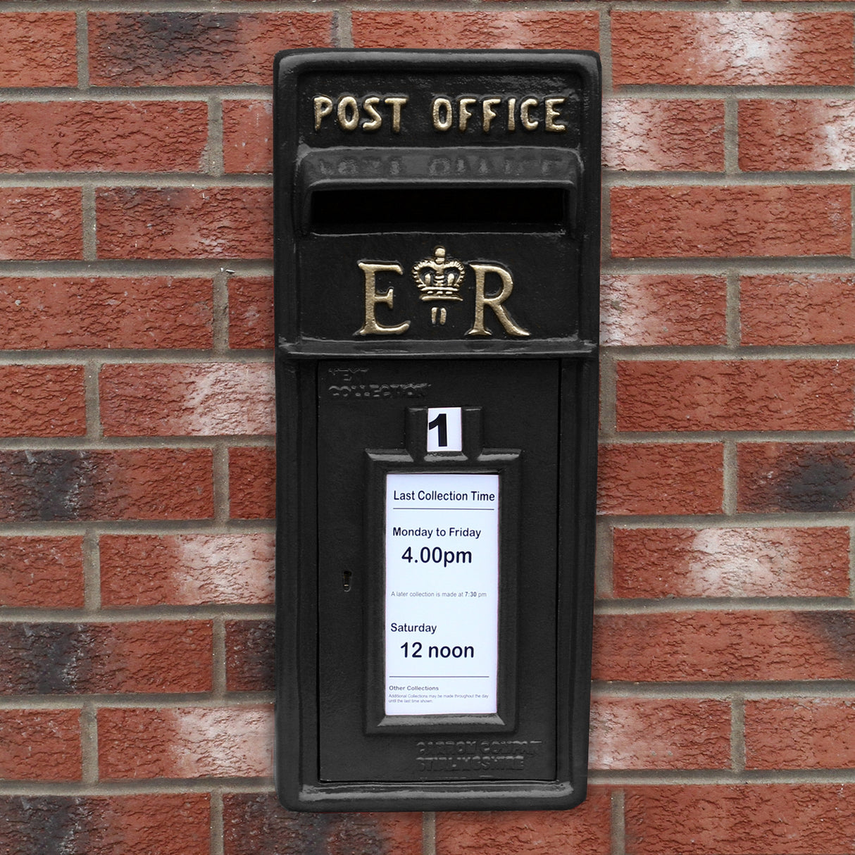Cassetta postale britannica nera con piedistallo, decorata con dettagli dorati e informazioni sulla raccolta affisse sul frontale
