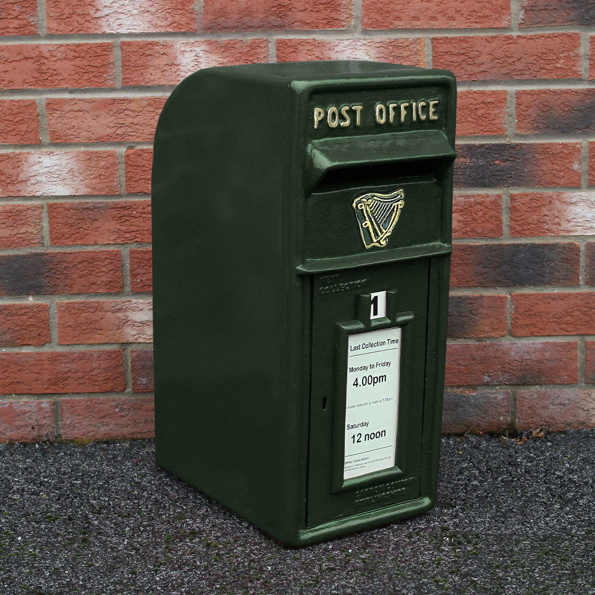 Cassetta postale britannica verde scuro con logo della Guinness, posizionata su un muro di mattoni rossi, elegante e vintage