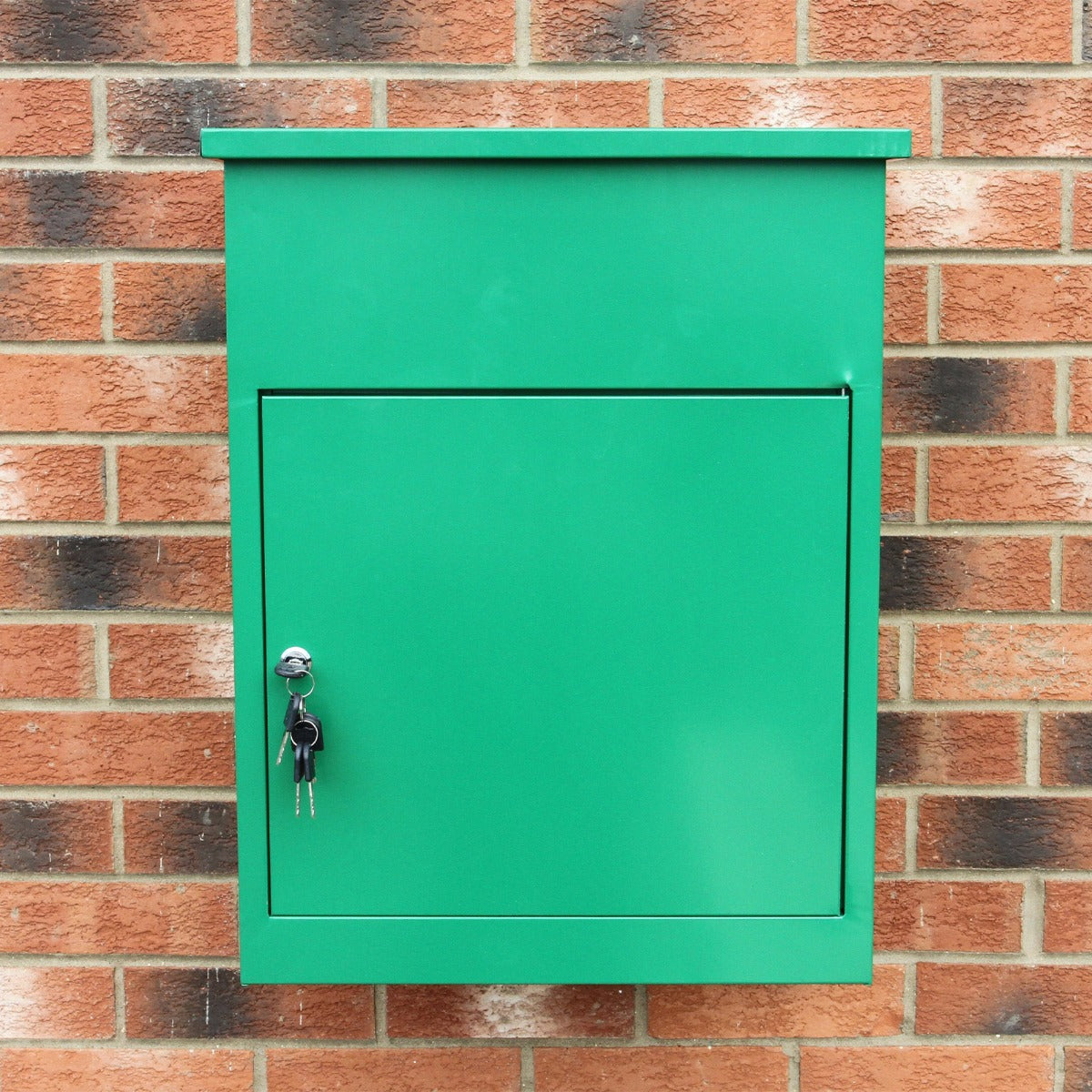 Cassetta postale per pacchi di colore verde brillante, con chiusura a chiave e superficie liscia, montata su muro di mattoni rossi