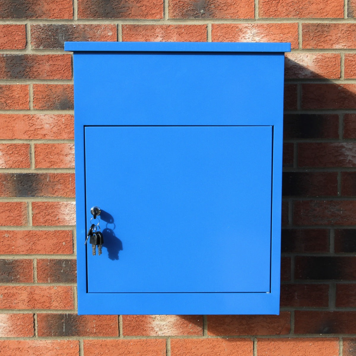 Cassetta postale per pacchi di colore blu brillante, con chiusura a chiave e superficie liscia, appesa a un muro di mattoni rossi