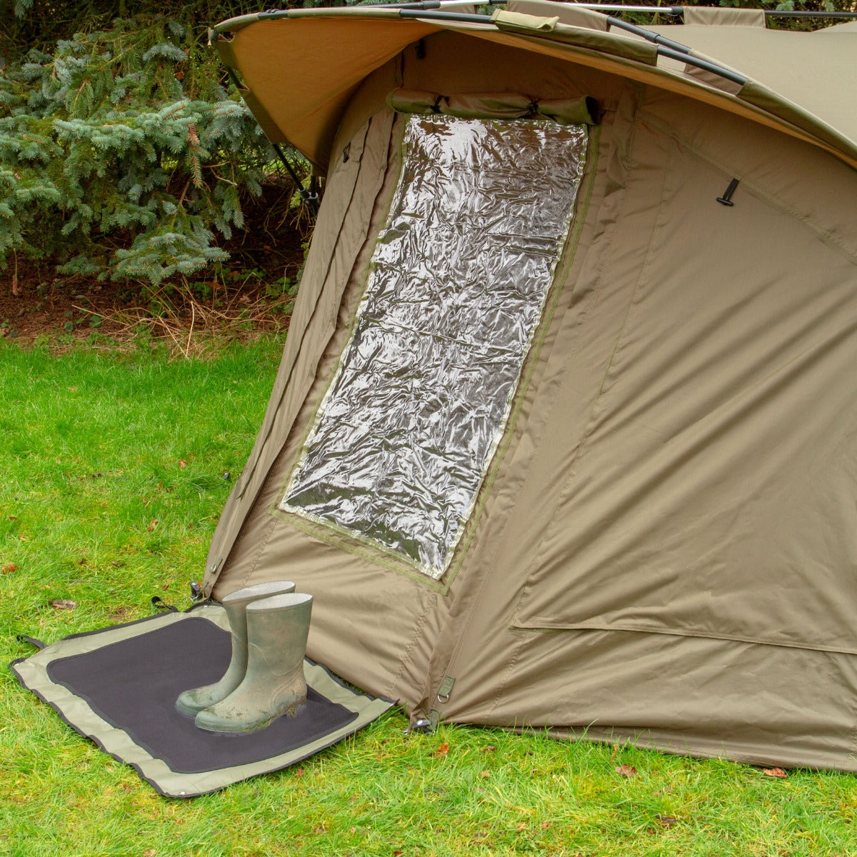 Tenda bivvy da pesca per 2 persone, colore beige, con finestra trasparente e stivali di gomma su un tappetino verde sul prato