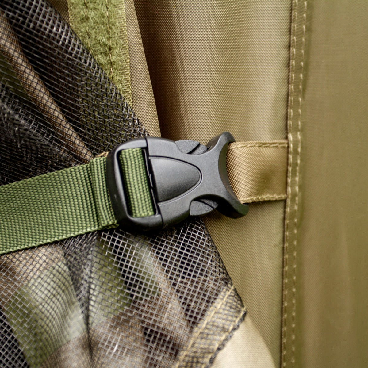 Dettaglio della chiusura in plastica nera della tenda bivvy da pesca, con tessuto verde e camouflage, evidenziando robustezza e praticità