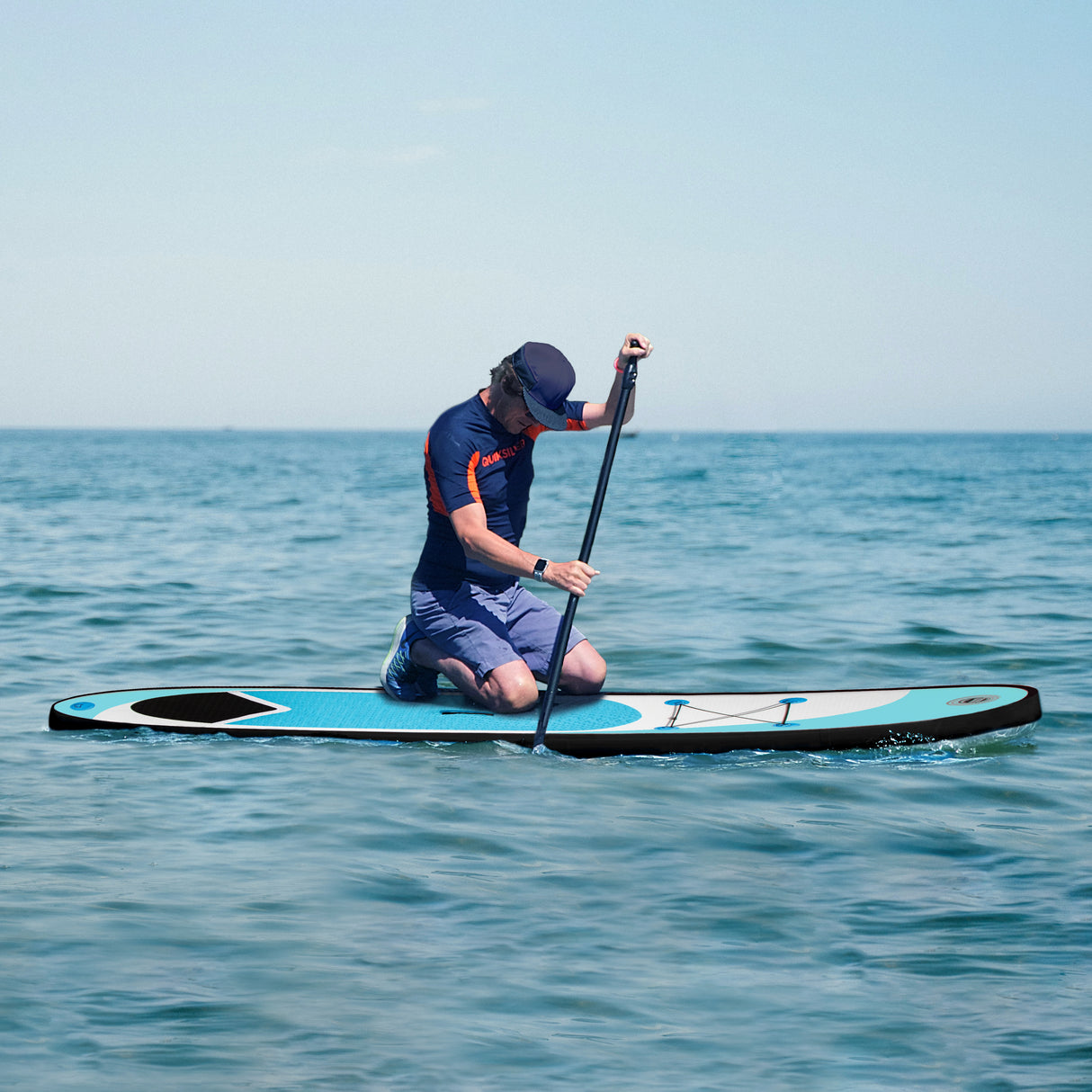 Tavola da surf SUP gonfiabile blu di 3 metri, con superficie antiscivolo e un uomo in ginocchio mentre pagaia in mare calmo