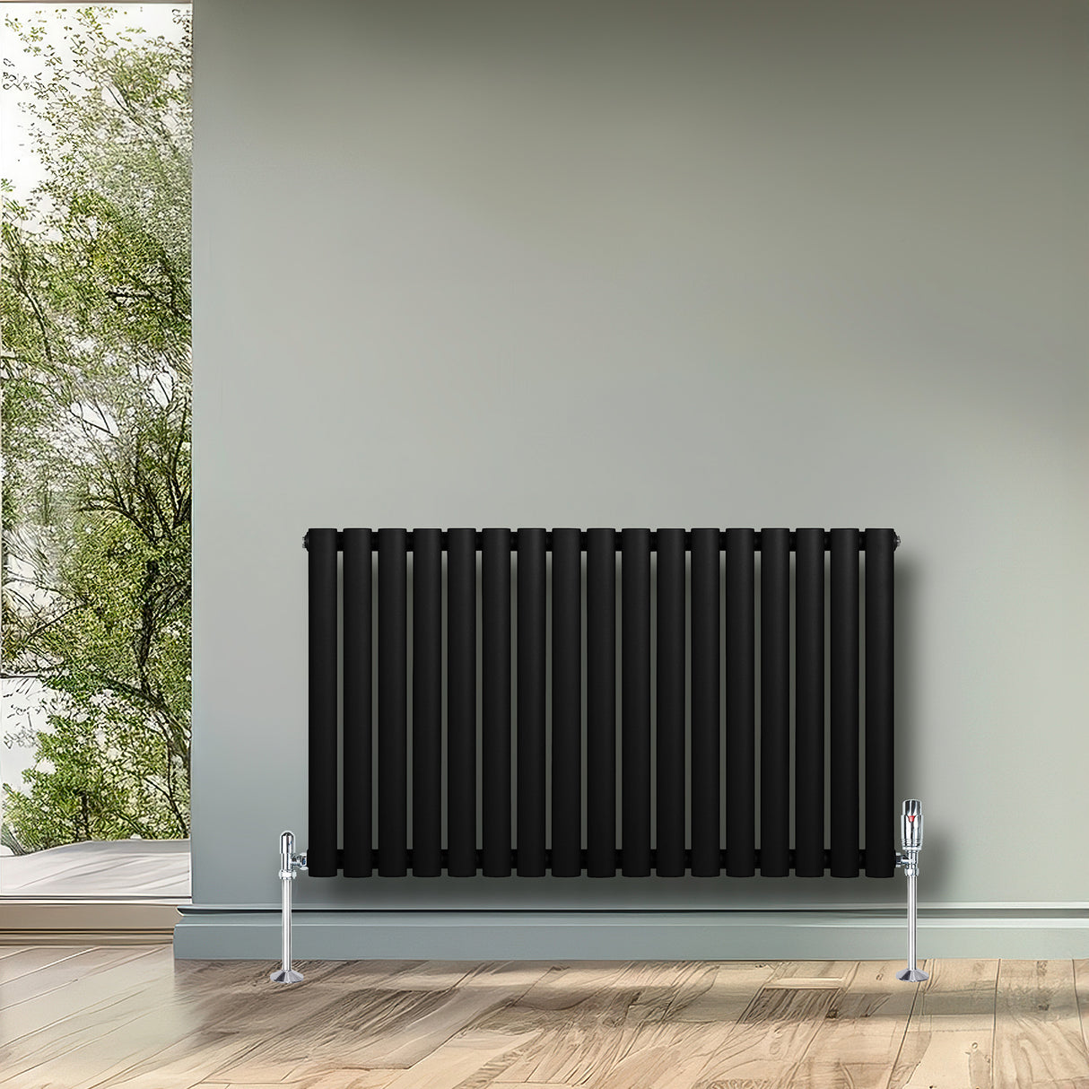 Radiatore ovale a colonna singola orizzontale, 600 x 1020 mm, finitura nera opaca, con valvole cromate, posizionato su parete chiara