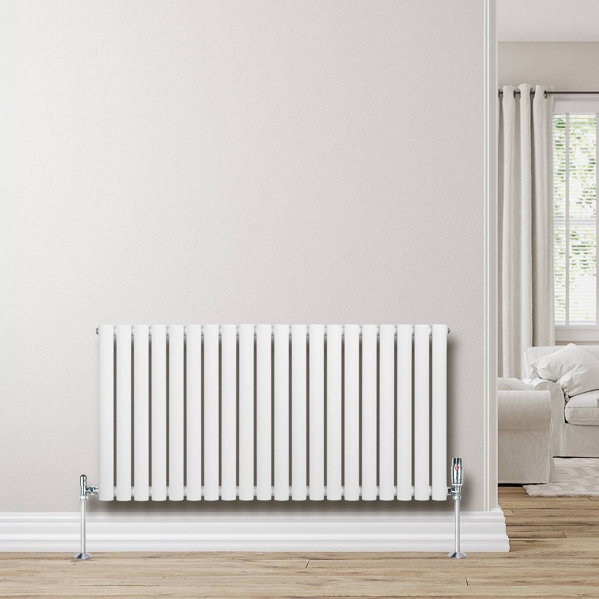 Radiatore ovale a colonna singola orizzontale bianco, con finitura liscia e valvole cromate, posizionato su parete chiara in un ambiente luminoso