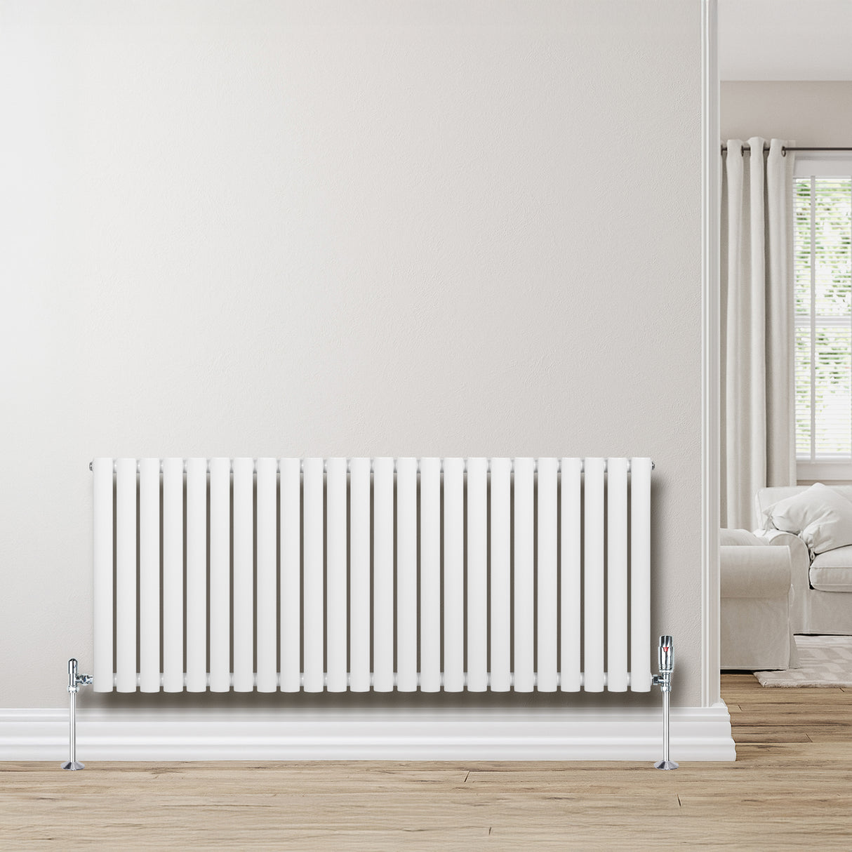 Radiatore ovale a colonna singola orizzontale bianco, con finitura liscia e valvole, posizionato su una parete chiara in un ambiente luminoso