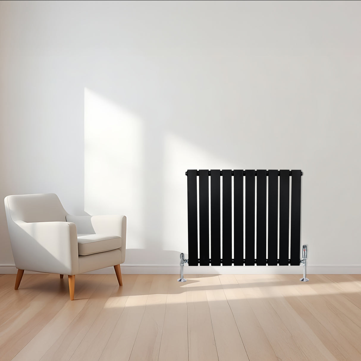 Radiatore piatto monocolonna nero, 600 x 700 mm, con finitura liscia e valvole, posizionato accanto a una poltrona bianca in un ambiente luminoso