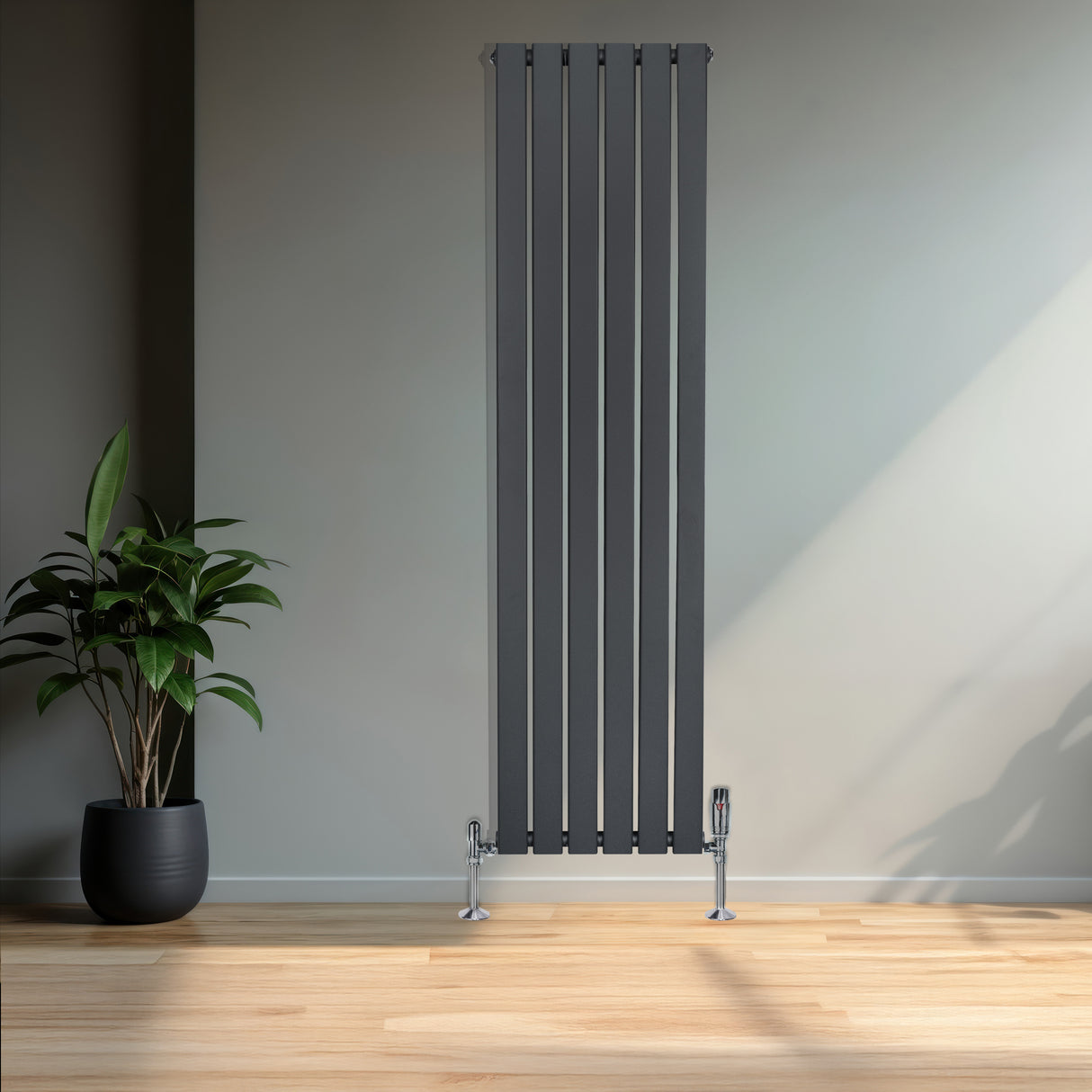 Radiatore piatto monocolonna grigio antracite, alto e stretto, con finitura liscia e valvole cromate, posizionato in un ambiente moderno con piante